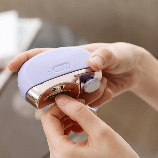 Purple electric nail clipper held in hand, safety cutter with guard