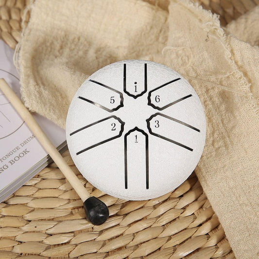 White mini tongue drum with numbered tone lines on top and black base