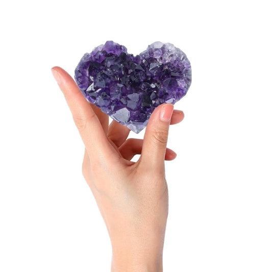 Amethyst crystal heart cluster with dark purple facets held in hands