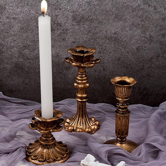 Ornate brass gold candlestick holder with fluted base, holding a white pillar candle