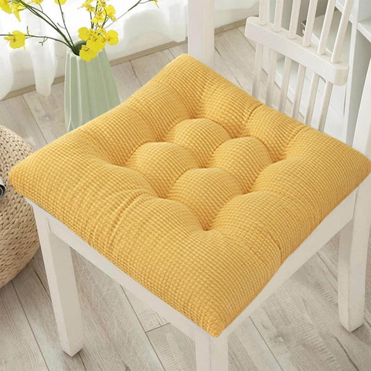 Yellow tufted corduroy seat cushion on a white chair, square padded cushion.