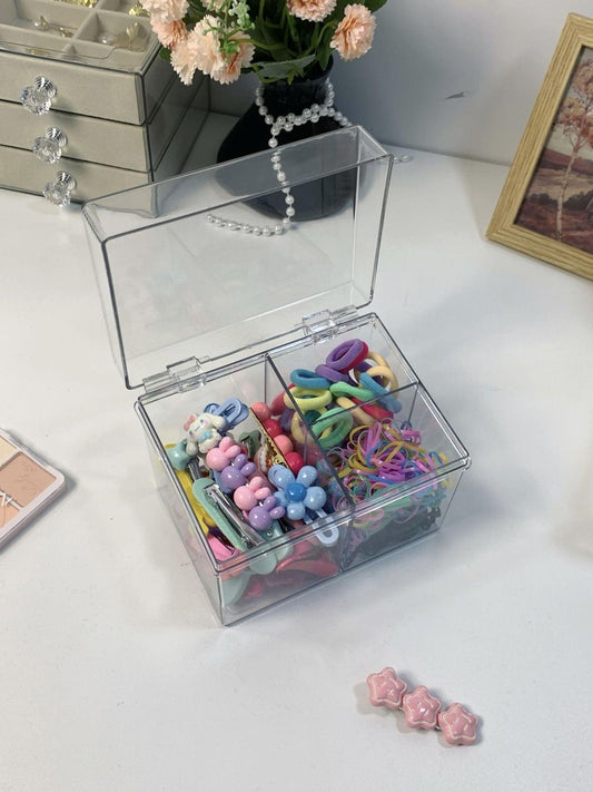 Clear three-compartment organizer box with assorted small colorful accessories