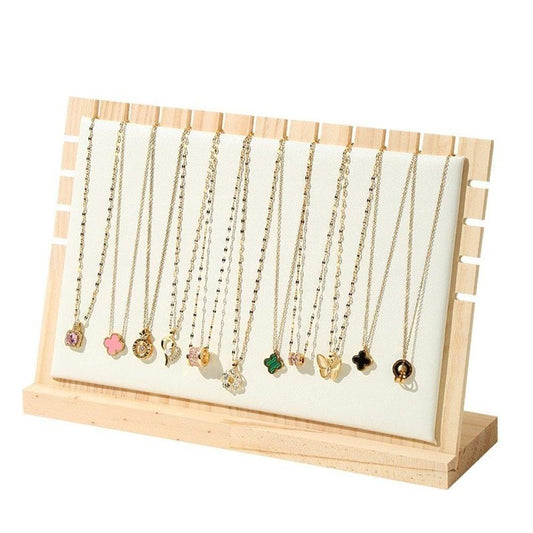 Beige wooden necklace display stand with white backing and dangling pendant necklaces