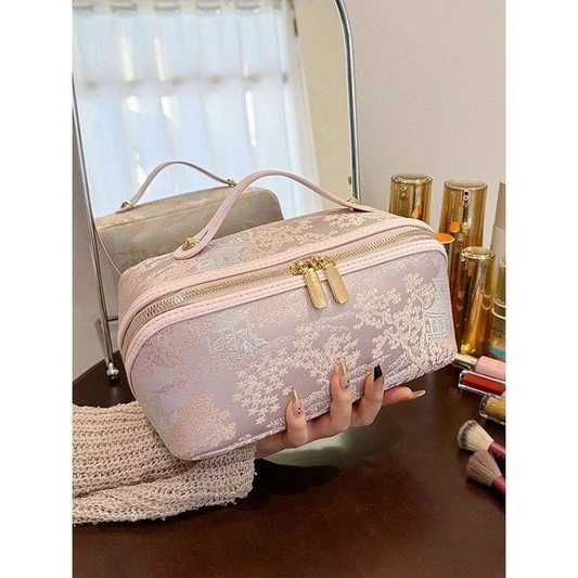 Pale pink zippered makeup bag with top handle and gold double zipper pulls.