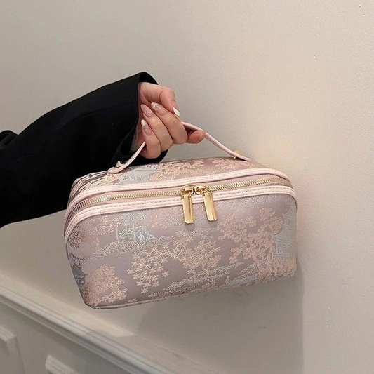 Pale pink cosmetic toiletry bag with top handle, zip closure, and gold double pulls.