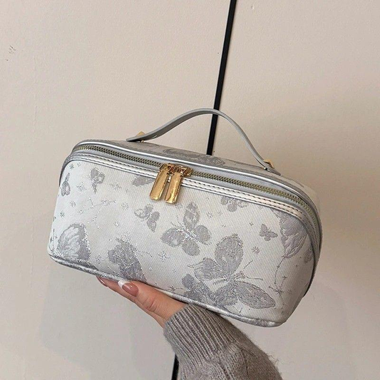 Vintage-style makeup bag with gold zipper and gray floral pattern, curved handle