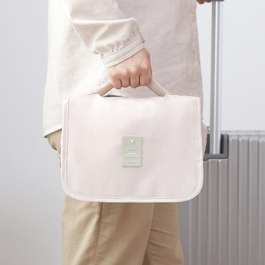 Beige hanging toiletry bag with hook, front label, and top carry handle