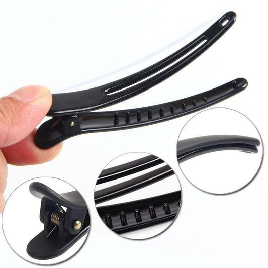 Black hair clip with comb-like teeth and metal hinge, close-up