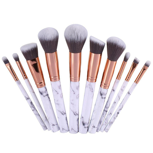 Makeup brush set fanned out with white marble handles, rose-gold ferrules, gray bristles