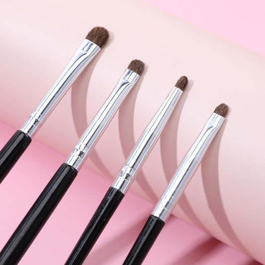 Close-up of four mini eye makeup brushes with silver caps, dark bristles, and black handles.