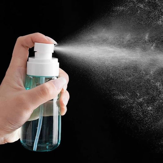 Refillable spray bottle with white nozzle, hand holding, fine mist spray