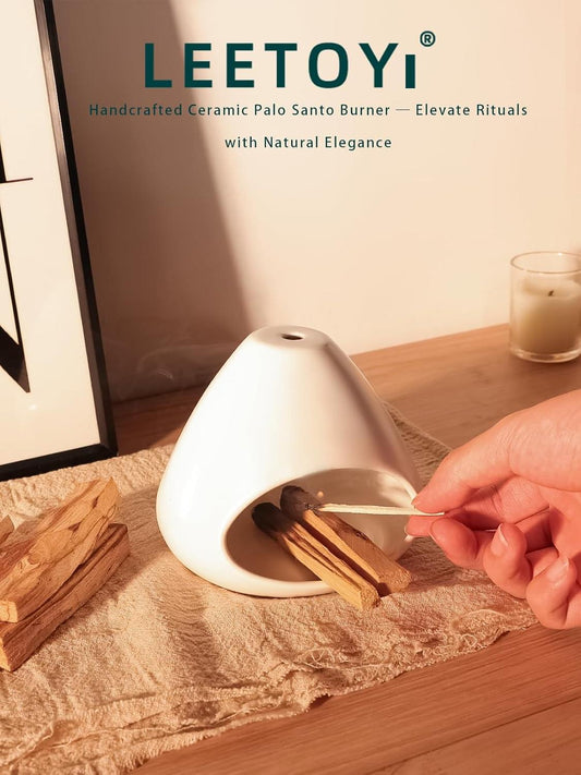 White ceramic incense holder with palo santo sticks being placed by hand