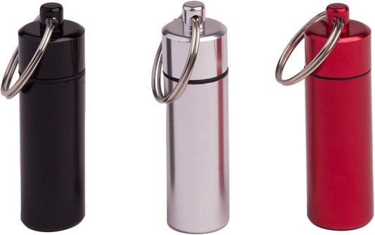 Cylindrical pill holder keychain containers in black, silver, and red with metal rings