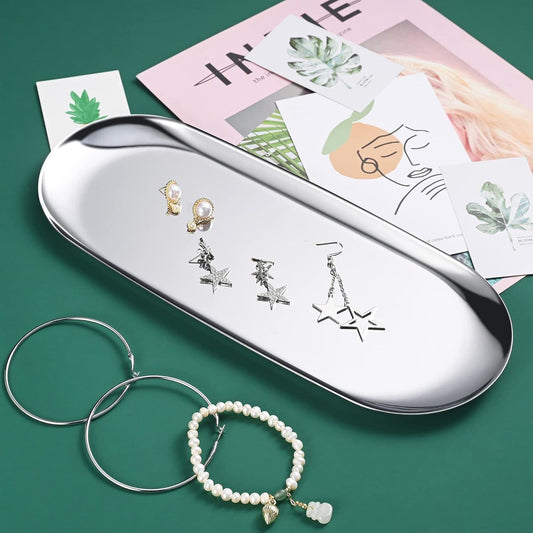 Stainless steel oval tray with earrings and a pearl bracelet displayed on the surface.