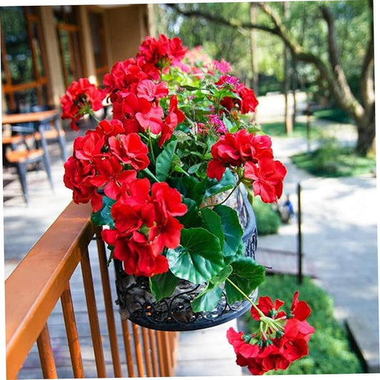 Artificial red geranium bouquet with green leaves in a dark planter, railing display