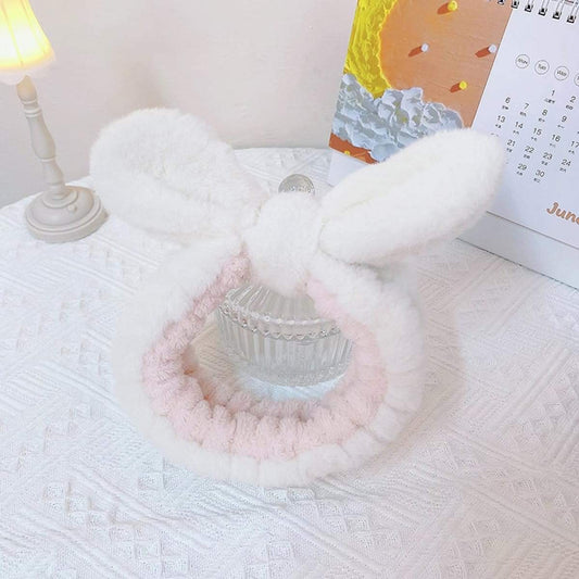 Fluffy bunny-ear face wash headband with pink inner ring, lying flat