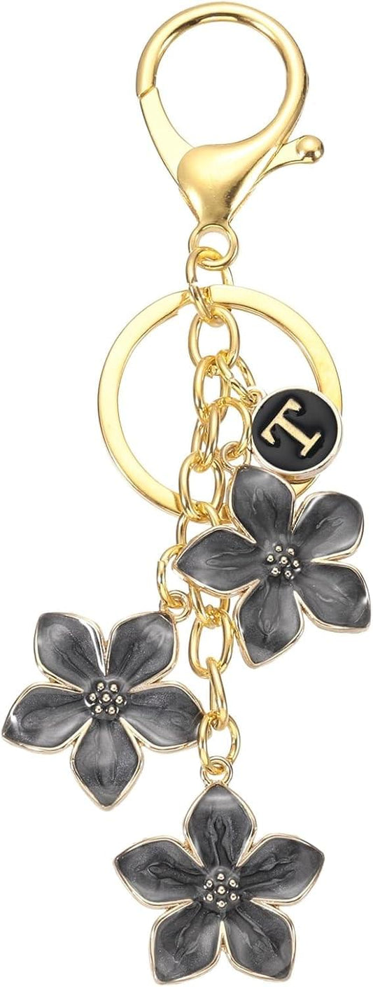 Gold keychain with circular ring and three dark flower charms, plus black letter T charm