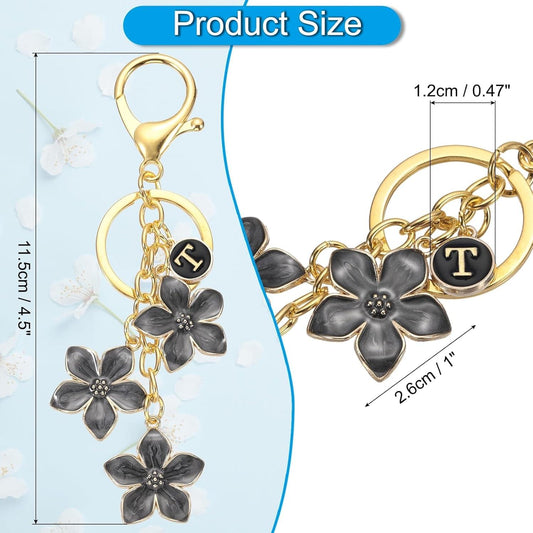 Gold keychain with hoop and chain, dark flower charms, and black T letter round charm