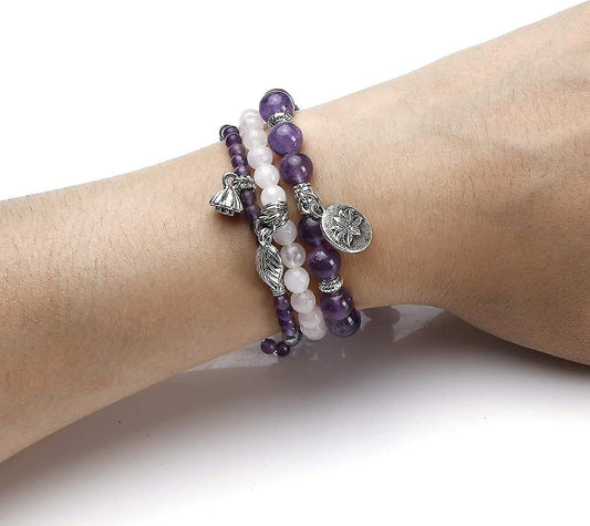 Three beaded bracelets on wrist: purple and white beads with leaf and charm pendants