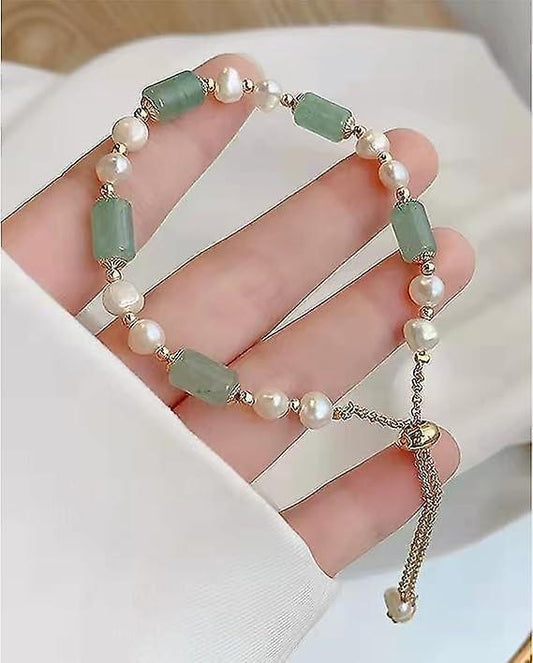Stacked jade and pearl bracelet set with green rectangular beads and small gold charms.