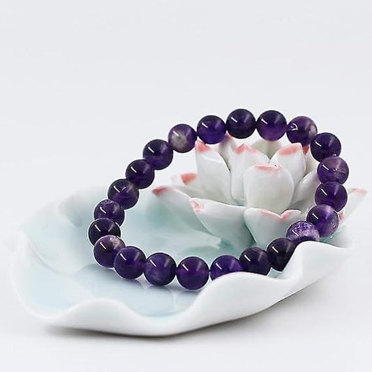 Purple beaded stretch bracelet with round stones on a white floral base