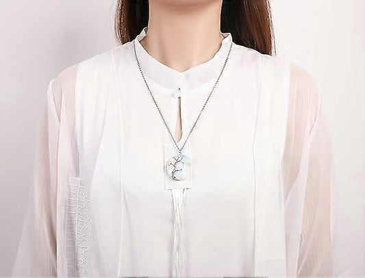 Crescent moon pendant necklace on silver chain with wire-wrapped tree design at center
