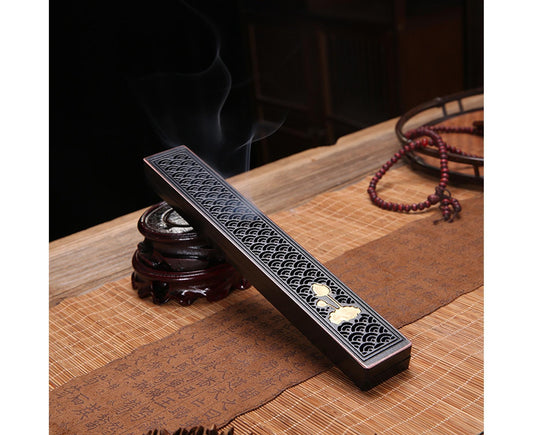 Black rectangular incense stick holder with looping lattice design and gold floral accents