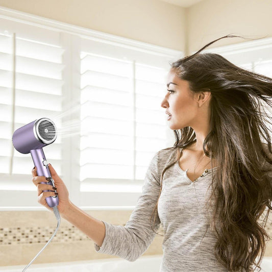 Handheld hair dryer in use with long cord, held near hair