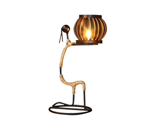 Abstract iron candle holder with small metal figure holding a glowing lantern candle
