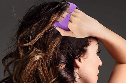 Purple scalp massager brush held against hair during shampoo