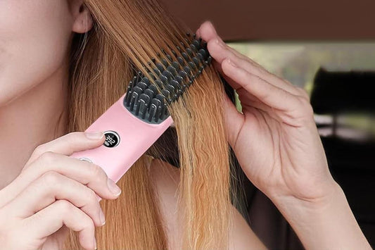Pink cordless hair straightening brush styling a section of hair