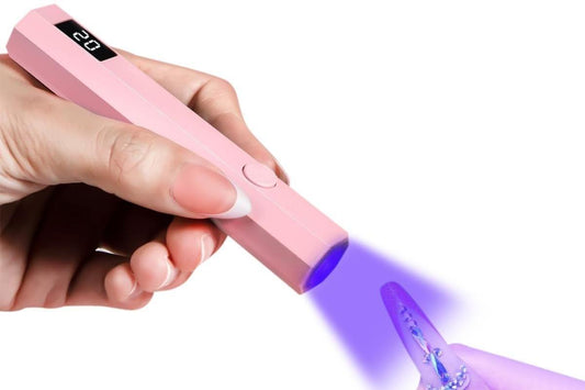 Pink handheld UV nail lamp held in hand, showing lit purple curing area