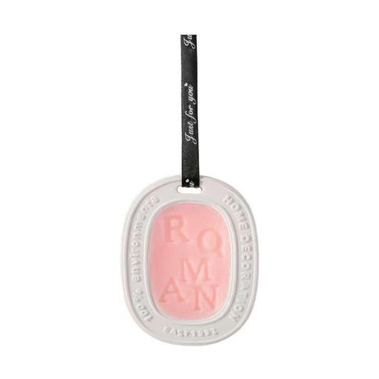 Aromatherapy wax tablet pendant with pink translucent insert and hanging black ribbon.