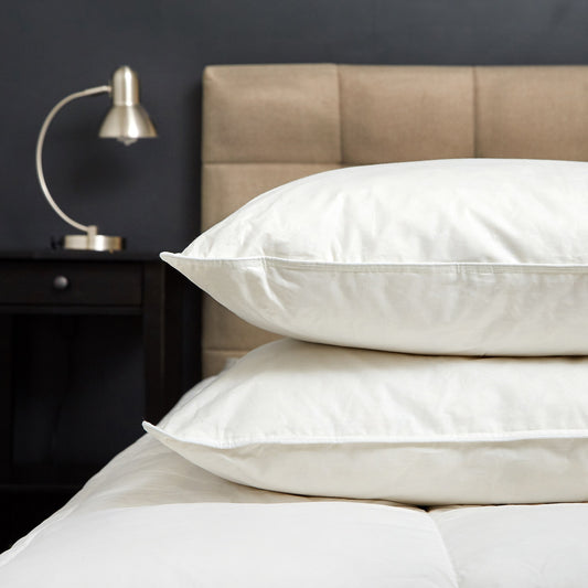 White down pillows stacked on a bed with quilt top visible