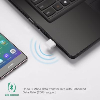 White USB Bluetooth adapter plugged into laptop USB port with signal waves