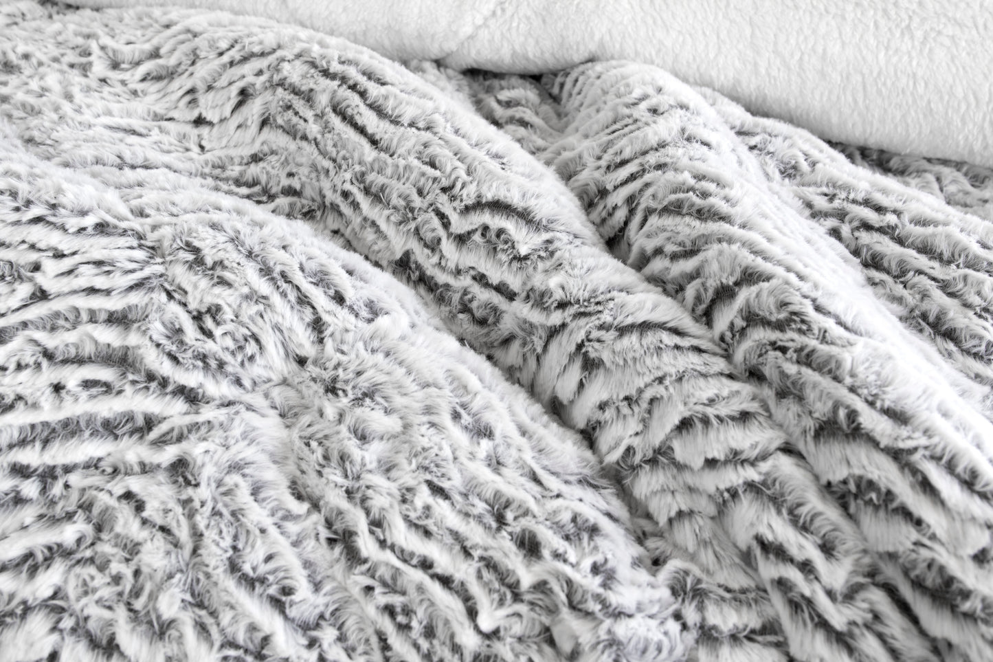 Light gray faux fur sherpa comforter with plush textured surface, close-up