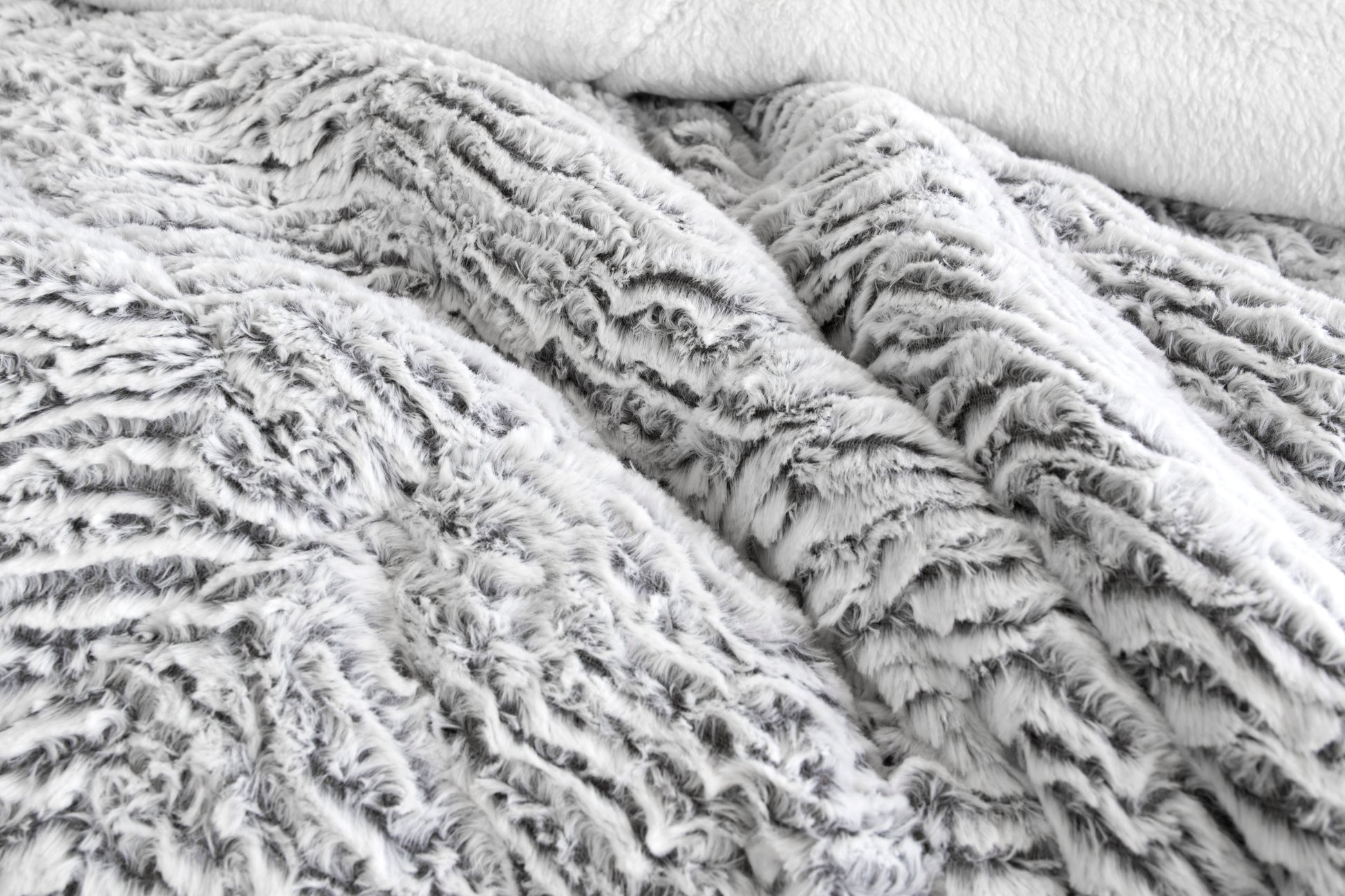 Light gray faux fur sherpa comforter with plush textured surface, close-up