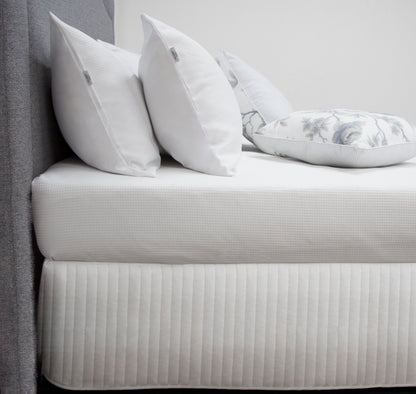 Quilted bed valance in white with stitched channel pattern and straight drop