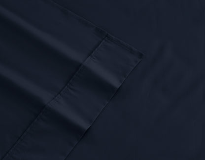Dark navy cotton-rich sheet fabric close-up with stitched edge and corner hem