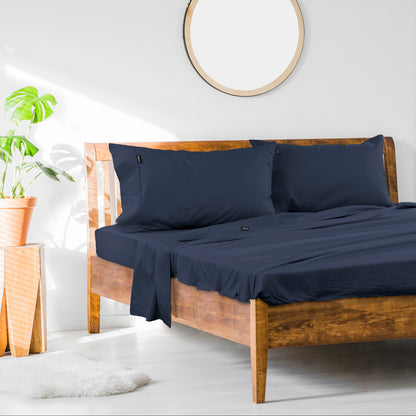 Navy cotton sheet set with pillowcases, fitted and flat sheets on a bed