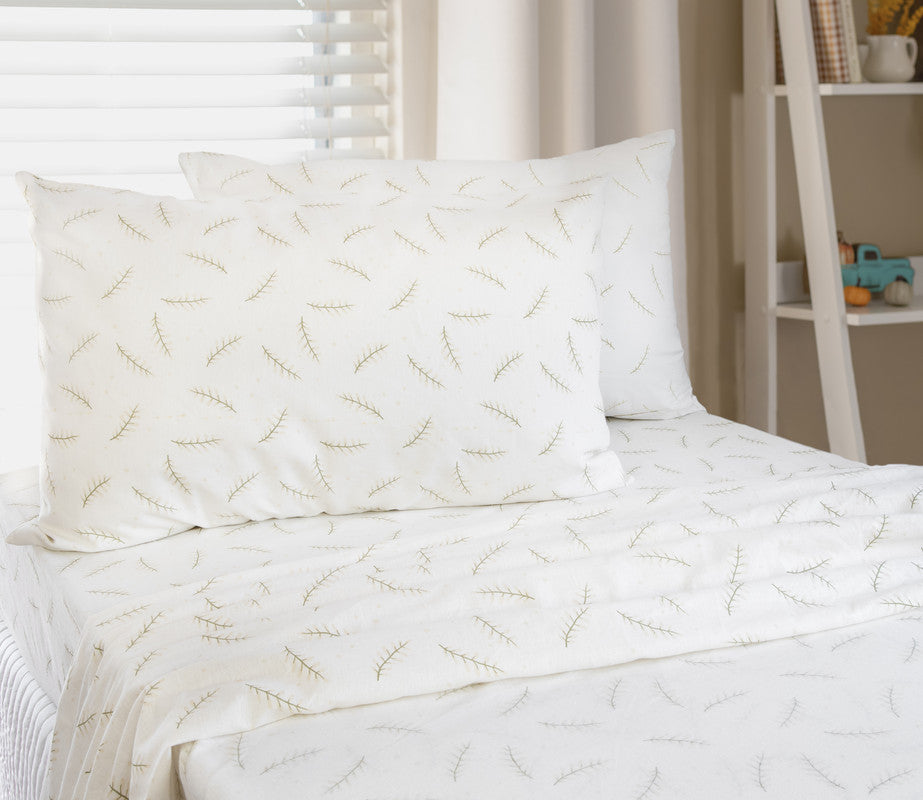 Single sheet set on bed with white pillowcases and green branch pattern