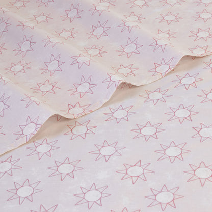 Pink bedding sheet with scattered starburst print, wrinkled fabric detail