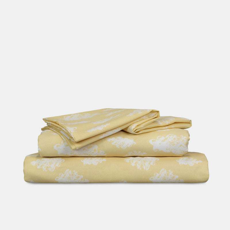 Folded single sheet set, yellow with white cloud pattern on stacked bedding