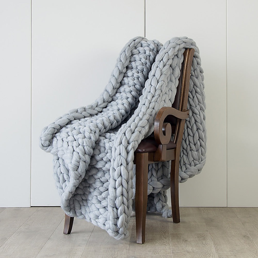 Chunky knit blanket in light grey, thick braided weave draped over chair back