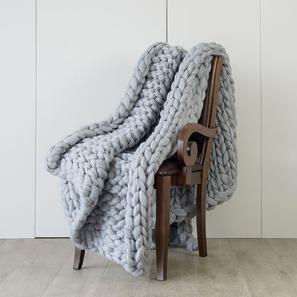 Chunky knit blanket in light grey, thick braided weave draped over chair back