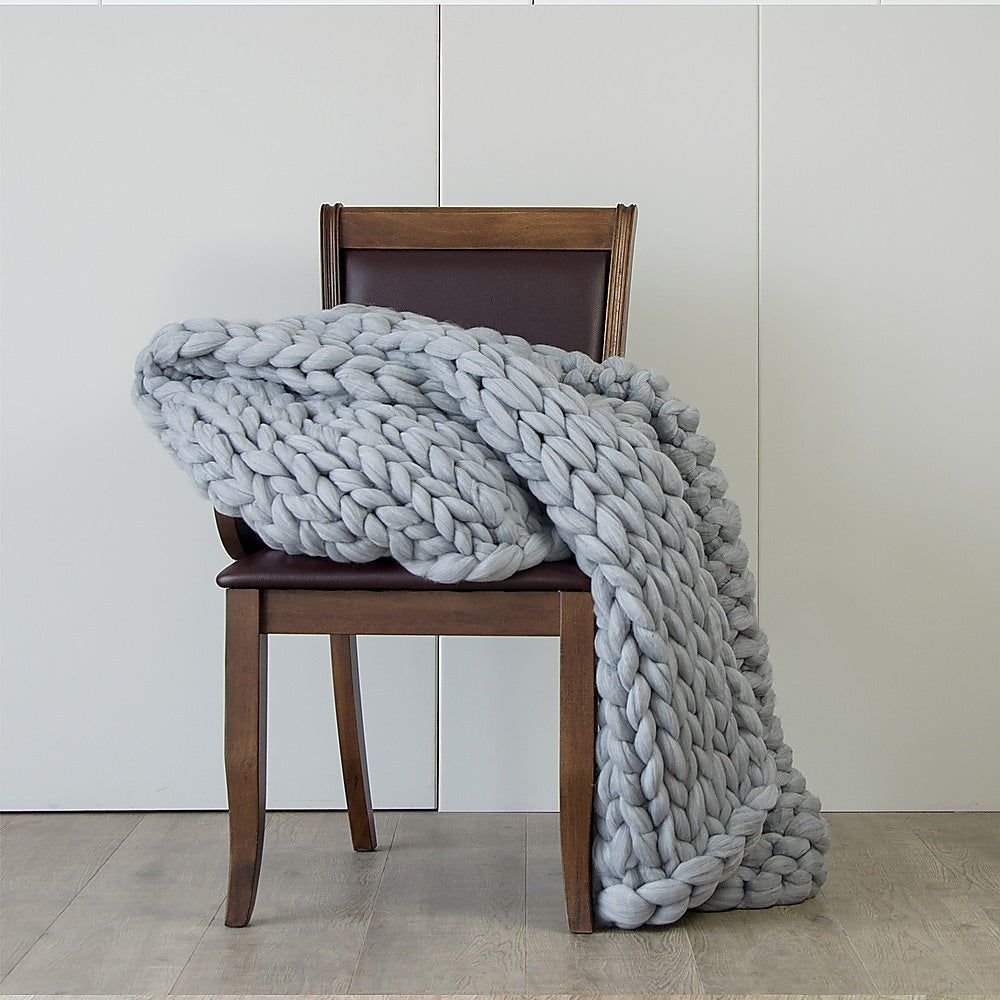 Chunky knit blanket in light grey, large braided weave folded over chair
