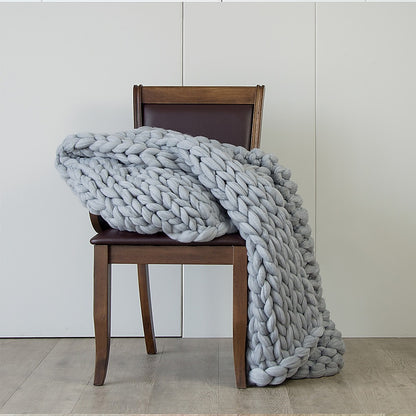 Chunky knit blanket in light grey, large braided weave folded over chair
