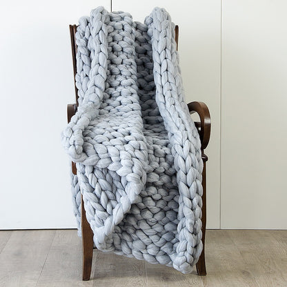 Chunky knit blanket in light grey, thick looped knit draped over chair