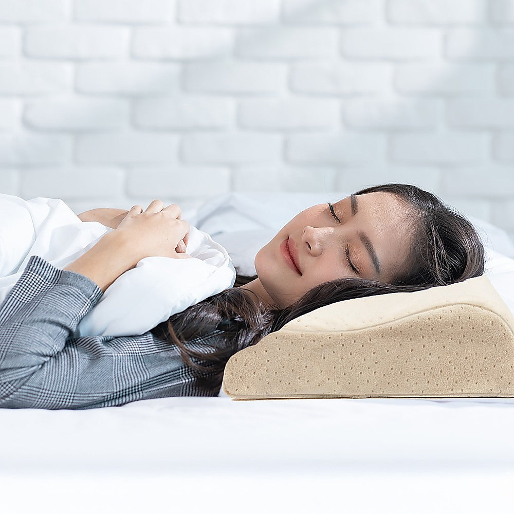 Light beige latex sleep pillow under head, curved profile with dotted surface texture