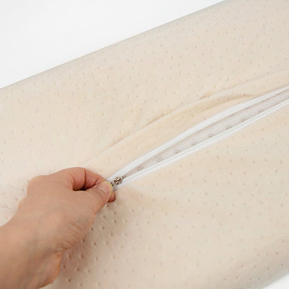 Latex pillow insert with zipper opening; hand pulls zipper on beige dotted cover